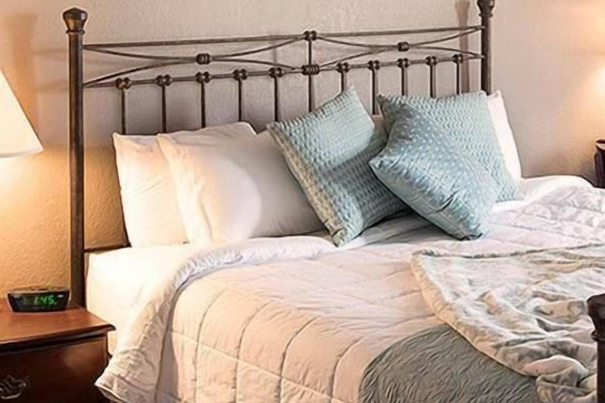 A bed with a metal frame, white bedding, and two light blue pillows.