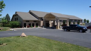 A building with a covered entrance, a parking lot, and a black pickup truck parked in the lot.