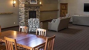 A dining area with a wooden table and chairs, a stone fireplace, and a living area with sofas and a TV.