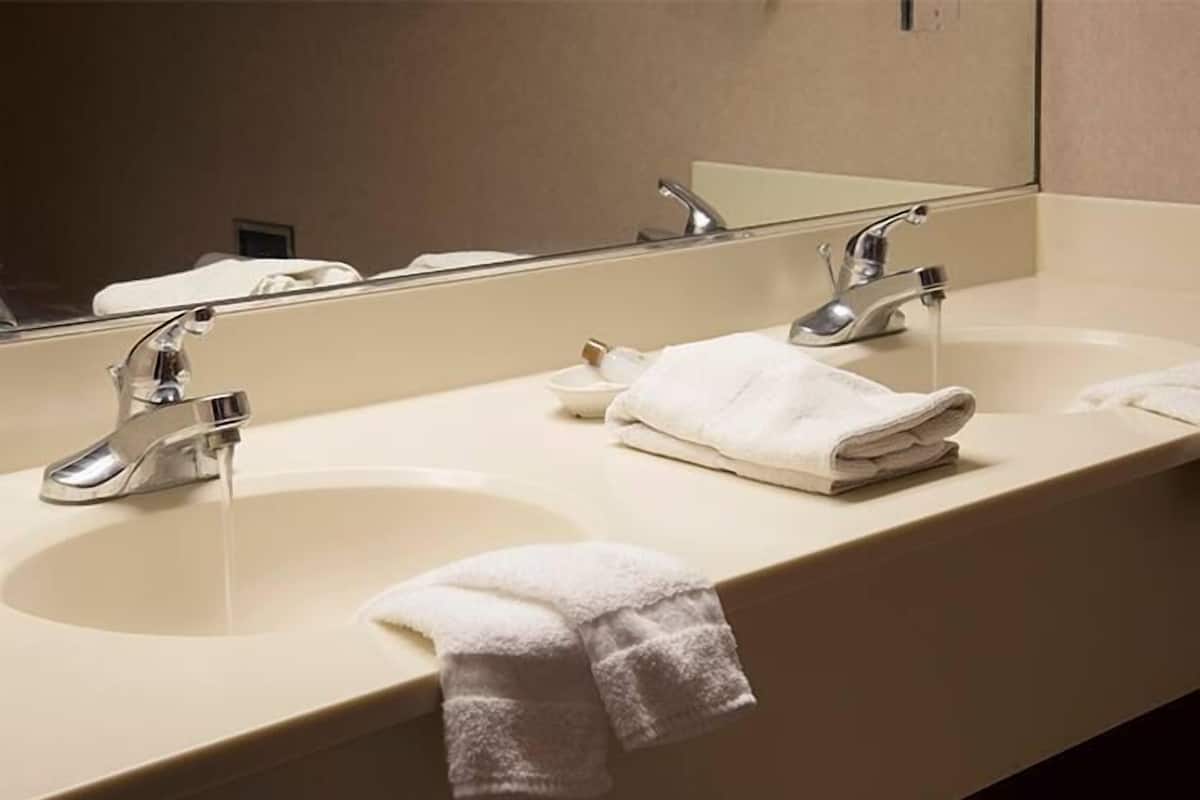 A bathroom with two sinks, a mirror, and a towel rack.