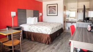 A hotel room with a bed, a desk, a chair, a table, a mirror, and a bathroom visible in the background. - Americas Best Value Inn Vandalia (Vandalia)