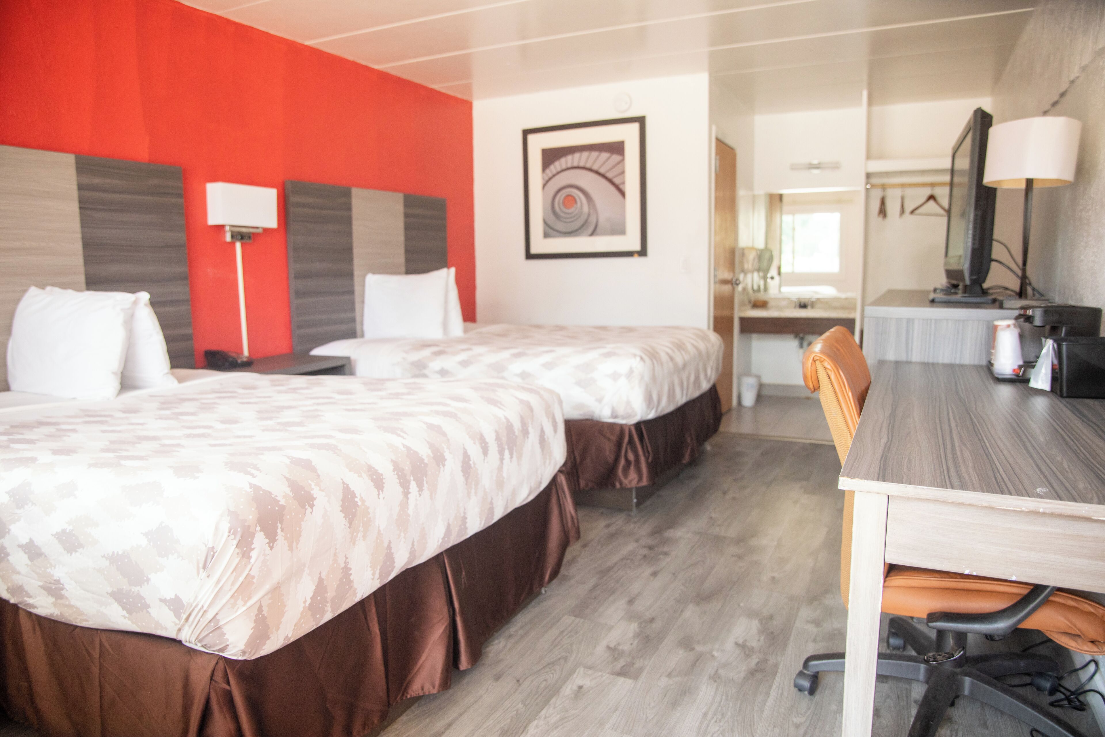 A hotel room with two beds, a desk, and a chair.