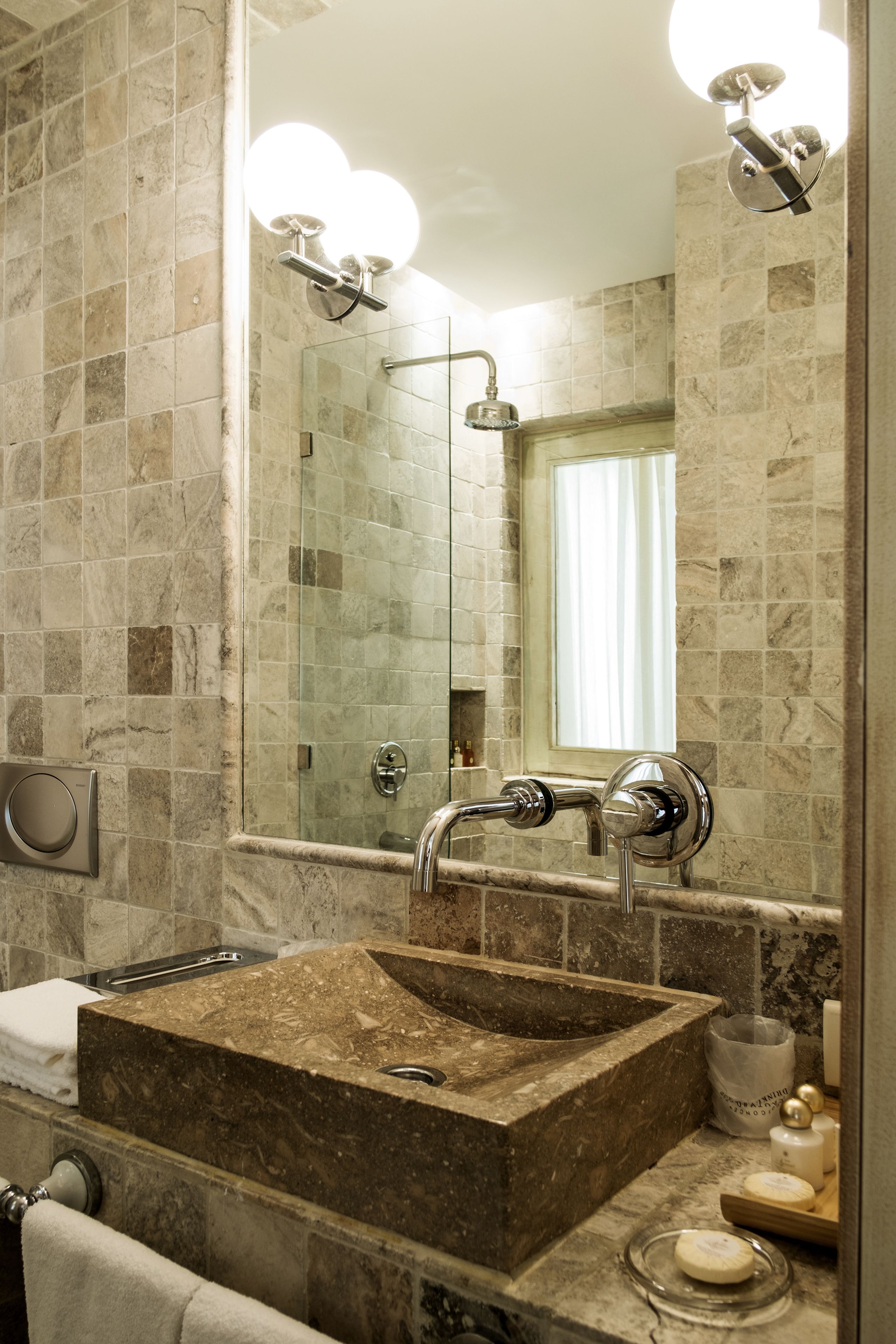 A bathroom with a marble sink, a glass shower enclosure, and a mirror with lights.