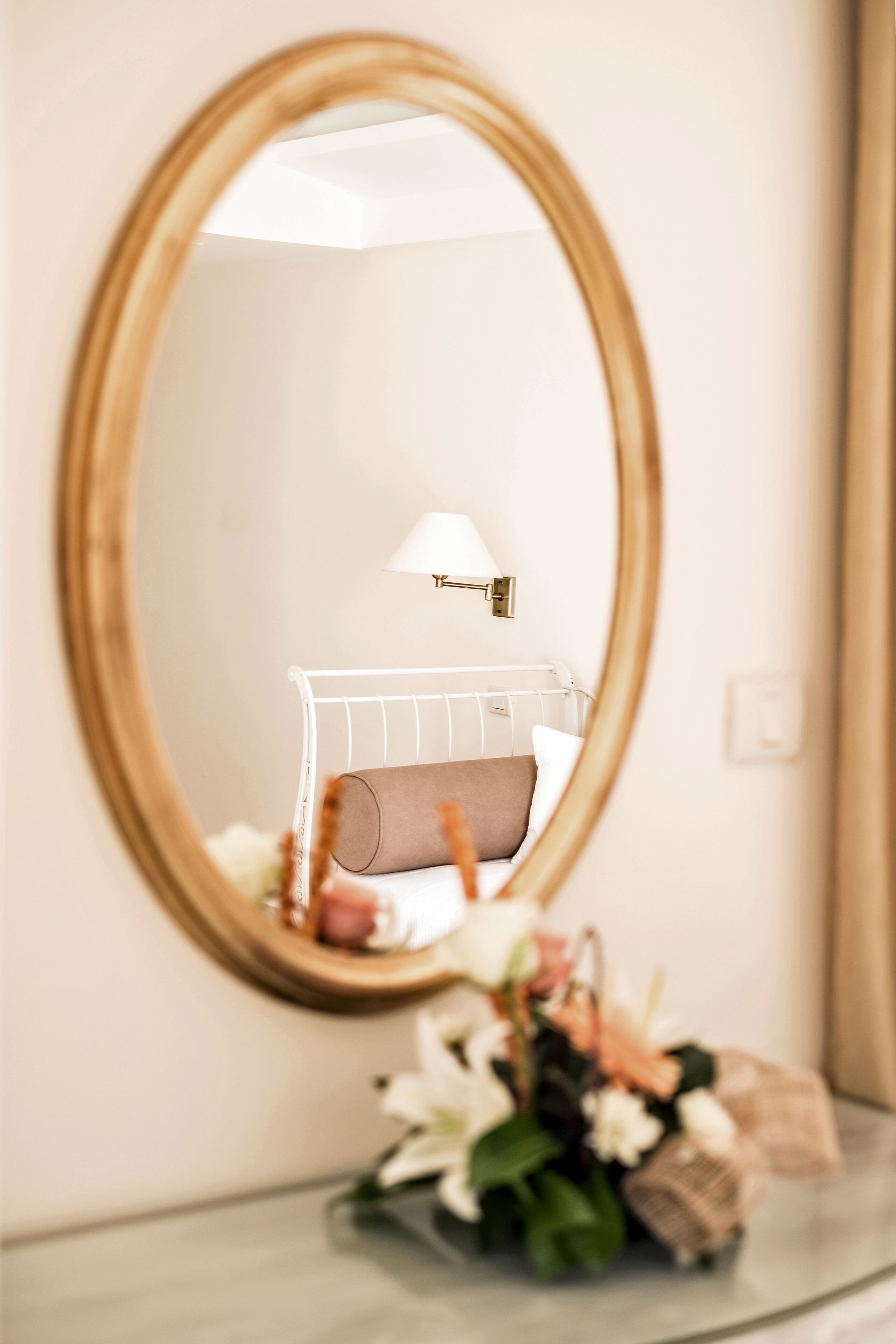 A bedroom with a bed, a bedside lamp, and a mirror on the wall.