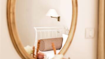 A bedroom with a bed, a bedside lamp, and a mirror on the wall.