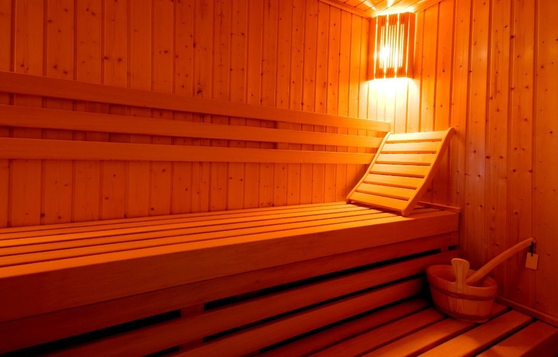 Een houten sauna met banken en een emmer.