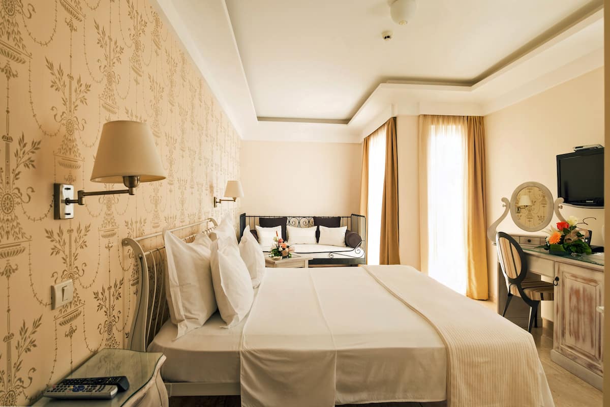 Une chambre d’hôtel avec un grand lit, un bureau avec une télévision et une lampe murale décorative.