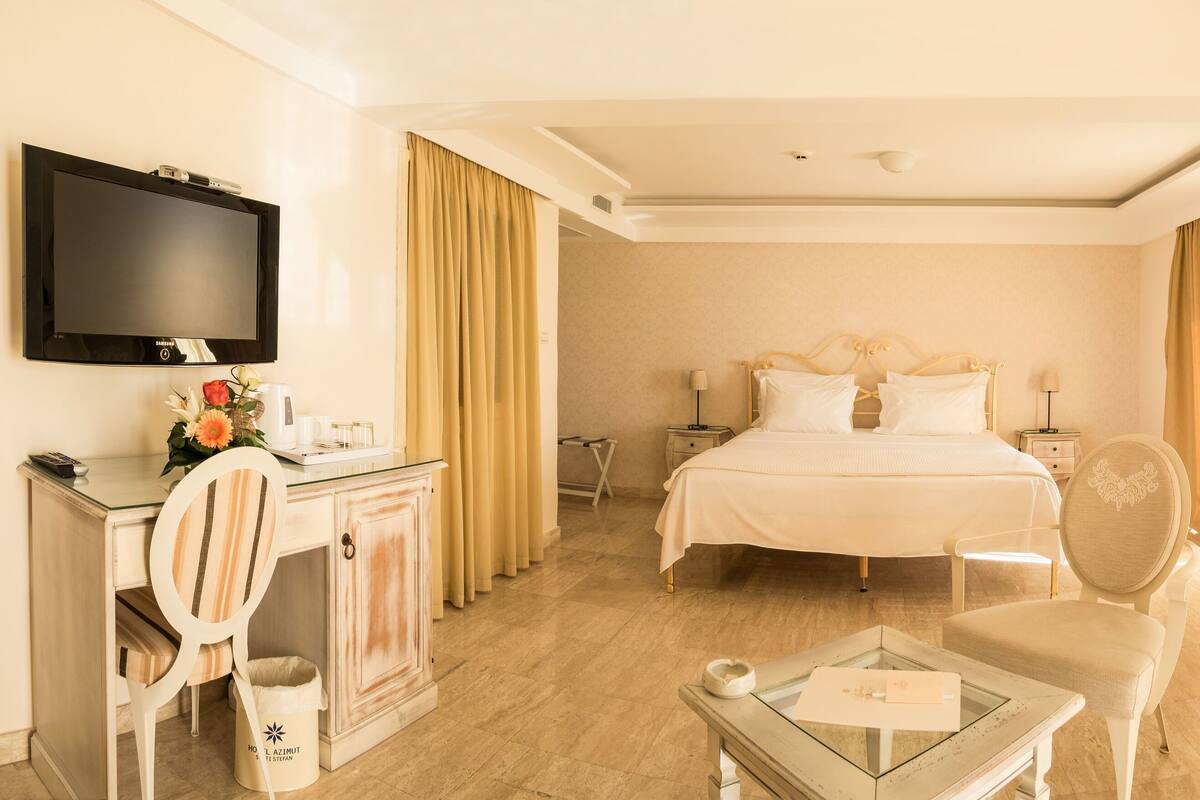Une chambre d’hôtel avec un lit, un bureau, une chaise, une télévision et un miroir.