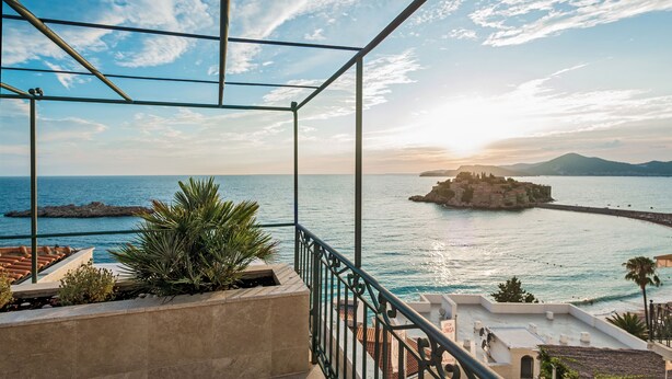 A balcony with a view of the sea, a rocky outcrop, and a distant island with buildings. - Hotel Azimut (Sveti Stefan)