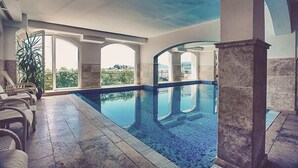 A swimming pool with clear blue water, surrounded by lounge chairs and a large potted plant. - Hotel Azimut (Sveti Stefan)