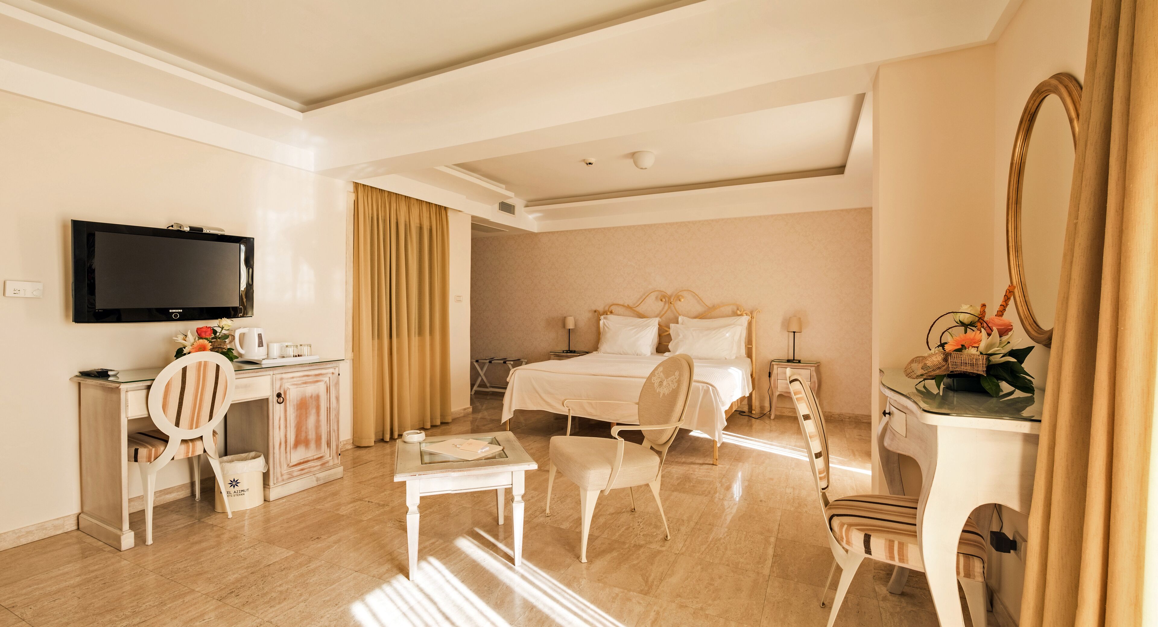 A hotel room with a bed, a desk, a chair, a TV, and a mirror.