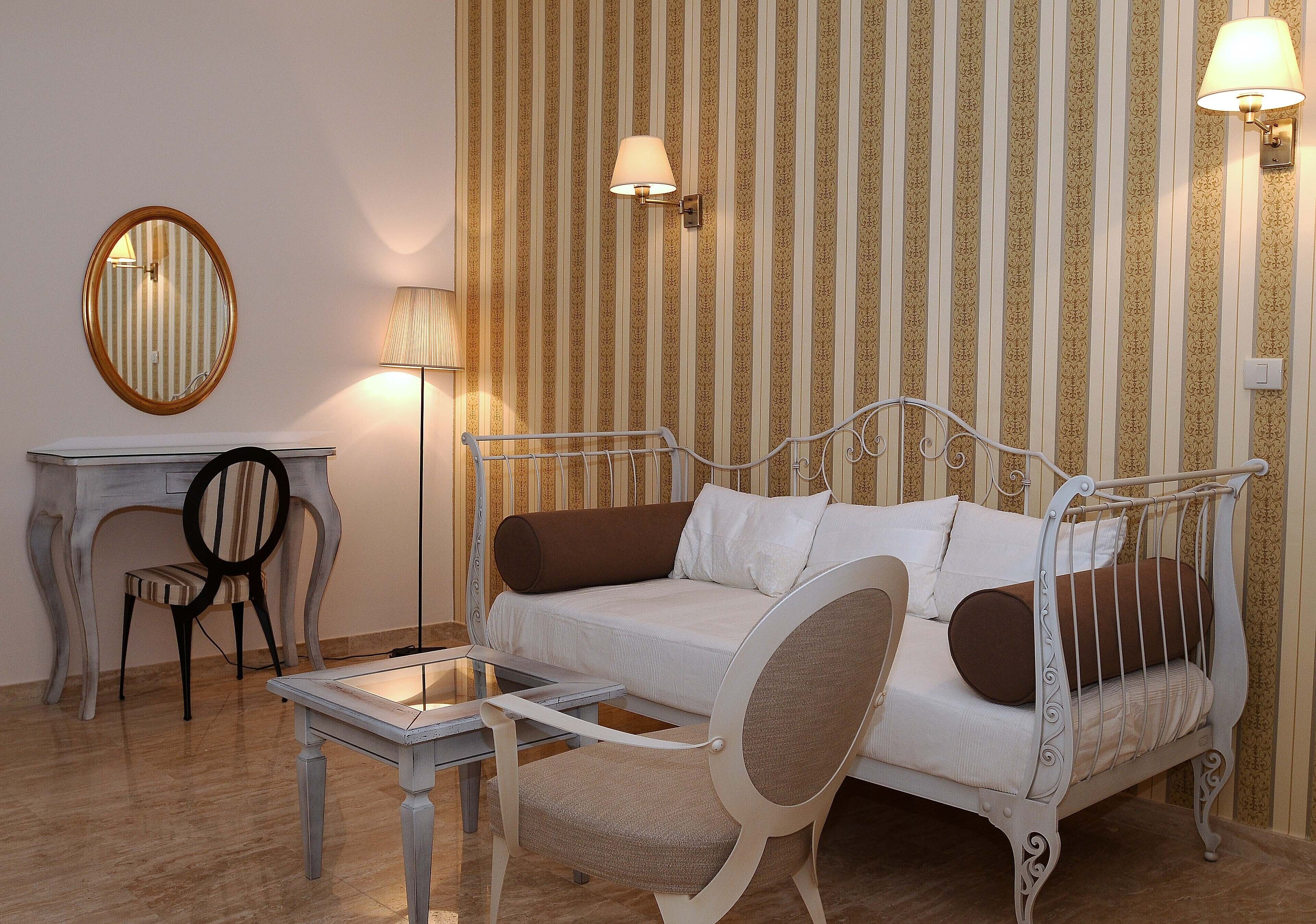 Una habitación con un sofá blanco, una mesita, una silla y una lámpara.