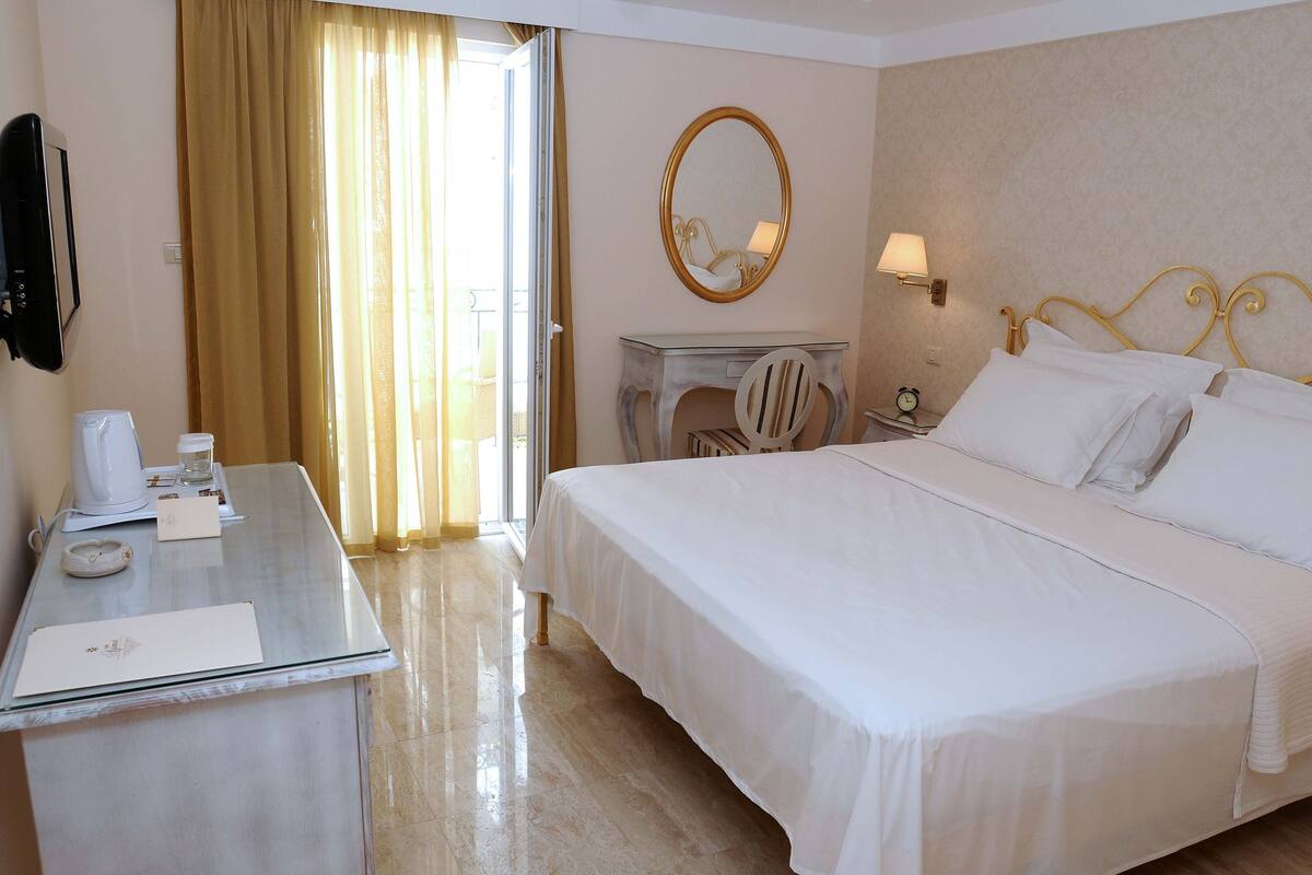 Une chambre d’hôtel avec un lit, une table de chevet, une lampe et un miroir au mur.