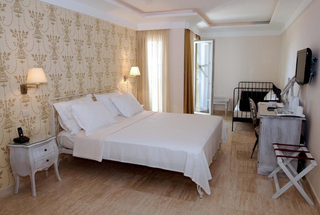A hotel room with a large bed, bedside lamps, a desk with a chair, and a television on the wall.