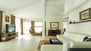 A modern living room with a TV, sofa, and a wicker chair. - Hotel Azimut (Sveti Stefan)