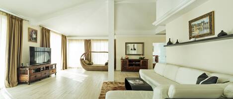 A modern living room with a TV, sofa, and a wicker chair.