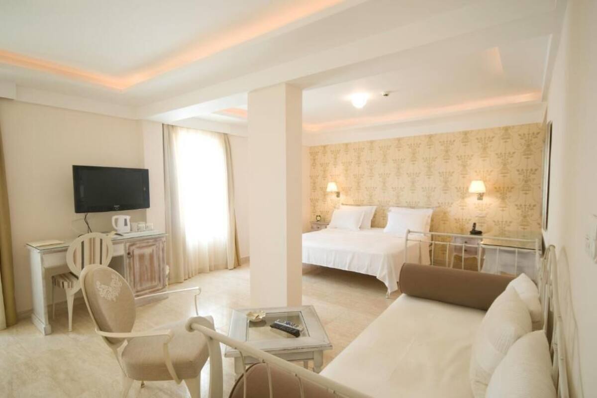 Une chambre d’hôtel comprenant un lit, un bureau avec une télévision, une chaise et un canapé.