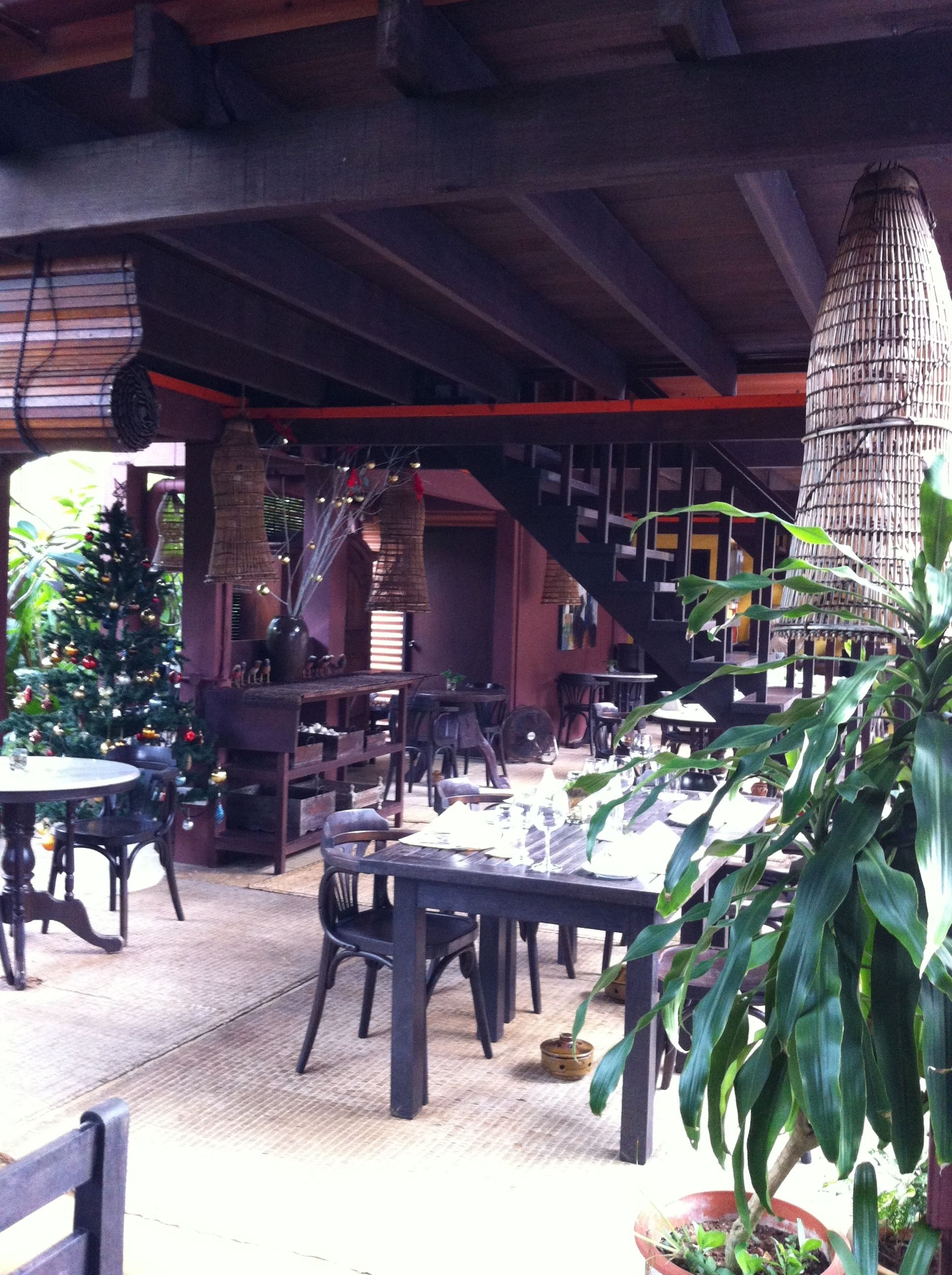 An indoor dining area with wooden tables and chairs, a Christmas tree, and hanging decorations.