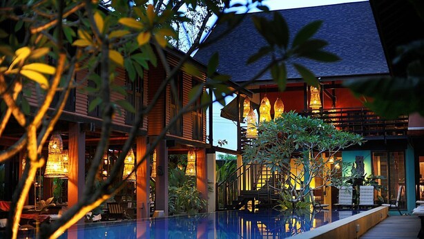 A poolside area with a wooden deck, lounge chairs, and a reflection pool. - The Village House (Kuching)