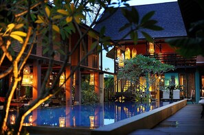 A poolside area with a wooden deck, lounge chairs, and a reflection pool. - The Village House (Kuching)