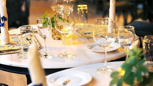 A restaurant setting with tables set for dining, featuring plates, glasses, and cutlery. - The Village House (Kuching)