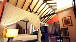 A bedroom with a canopy bed, a TV, a bedside table, and a chair. - The Village House (Kuching)