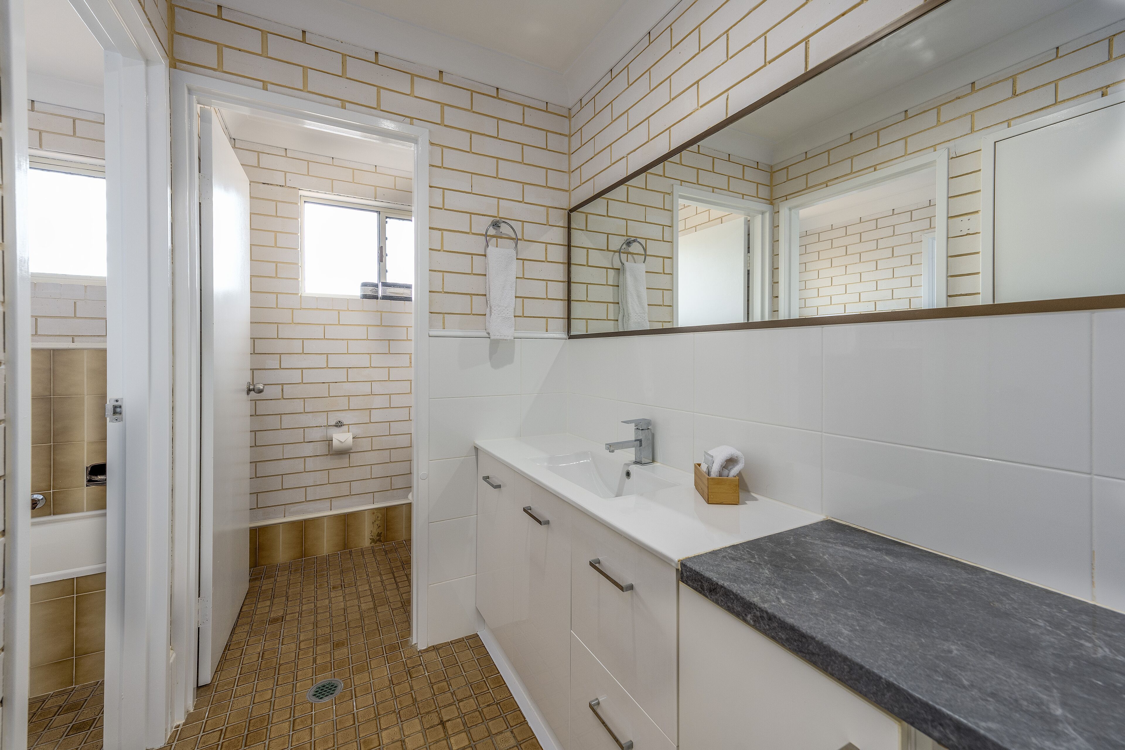A bathroom with white subway tiles, a black marble countertop, and a mirror above the sink.