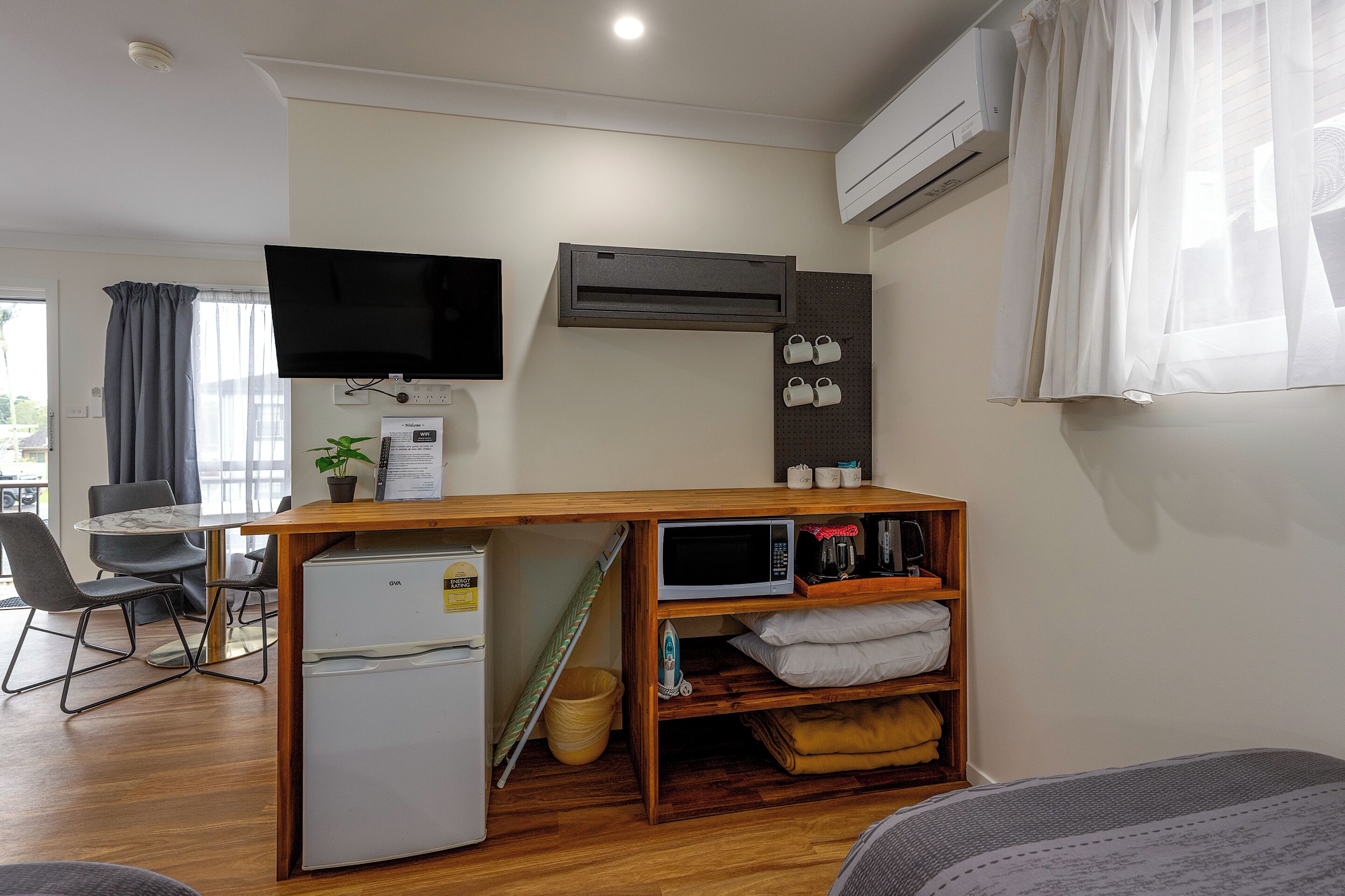 A compact living space with a kitchenette, a flat-screen TV, a ceiling fan, and a dining area with a table and chairs.