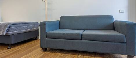 Una sala de estar moderna con un sofá gris y un sillón gris más pequeño, ambos con patas de madera.