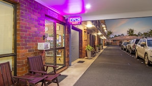 A hotel entrance with a closed shutter, a neon 'OPEN' sign, and a 'PLEASE SLIDE' sign. - Coast Inn Motel (Ballina)