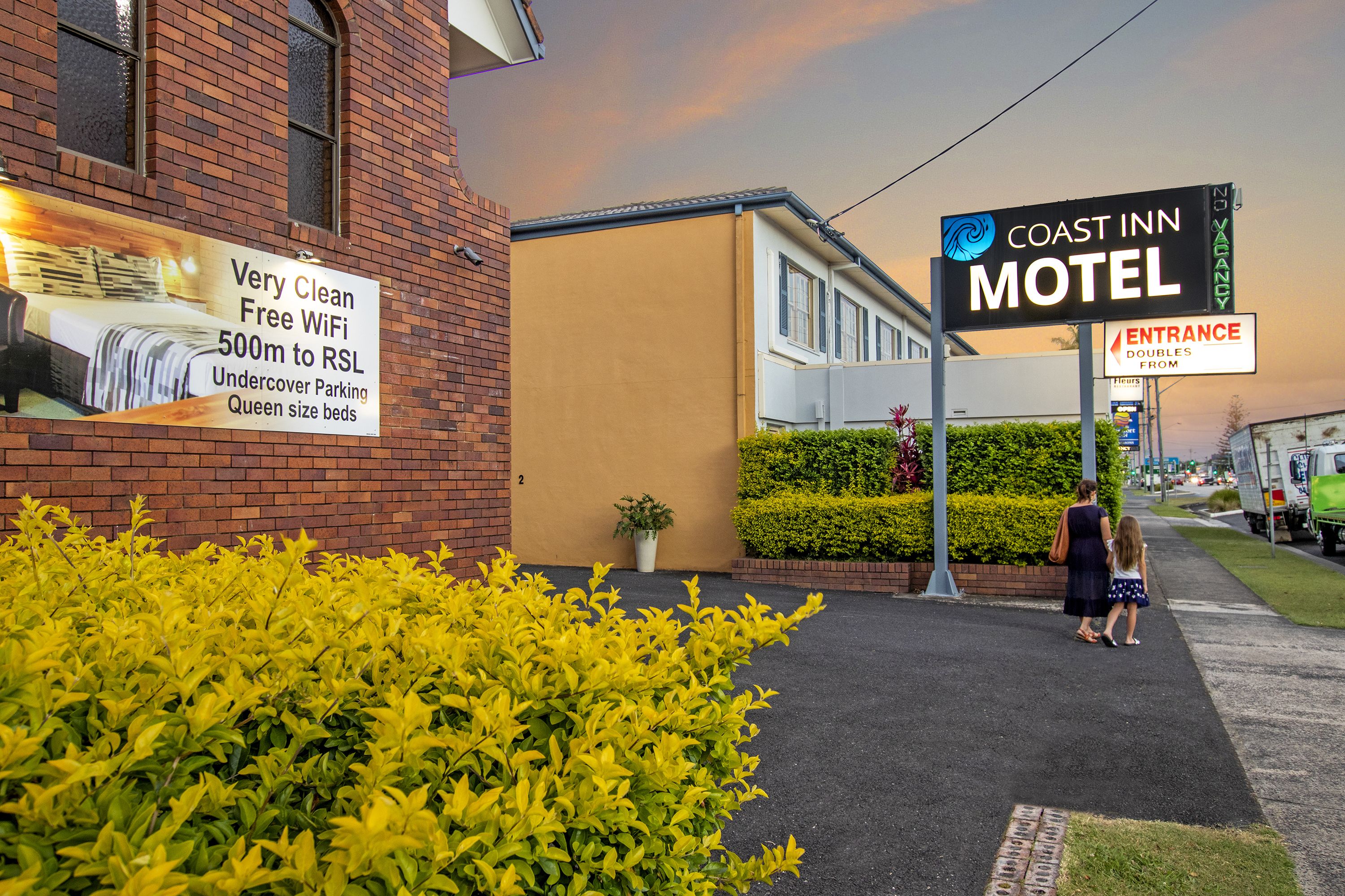 Segnaletica di un motel con servizi tra cui WiFi gratuito, parcheggio coperto e letti queen size.