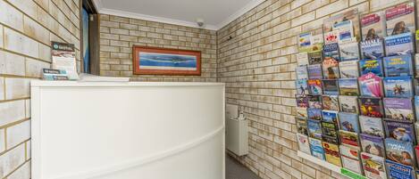 A reception area with a brick wall, a framed picture, and a bulletin board with travel brochures.