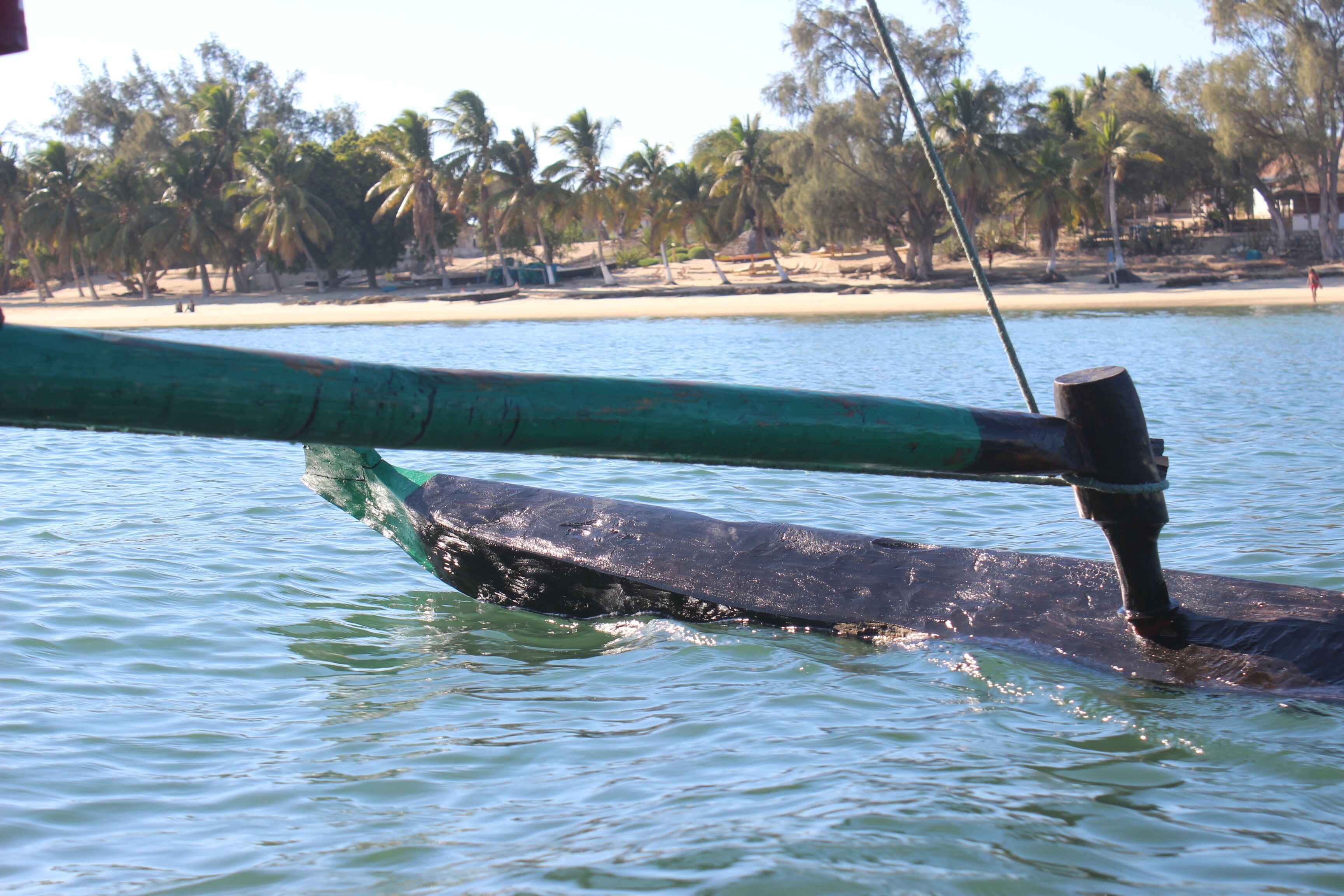 A boat with a green and black hull on calm water.