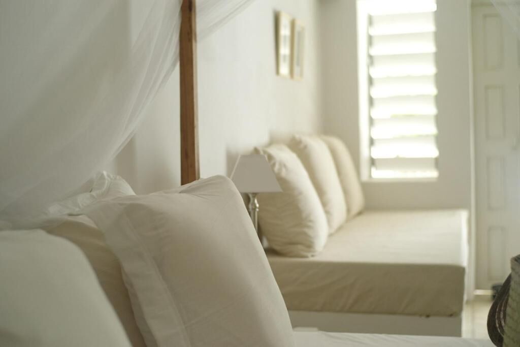 A bedroom with a bed, a bedside table, a lamp, and a window with blinds.