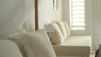 A bedroom with a bed, a bedside table, a lamp, and a window with blinds.