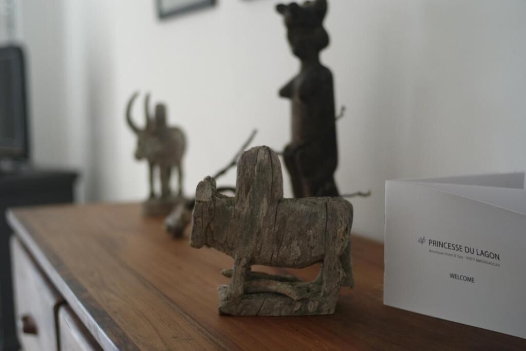 Une table en bois ornée d’une sculpture rustique représentant un taureau et un ours, ainsi qu’une pancarte blanche sur laquelle on peut lire « PRINCESSE DU LAGON » et « BIENVENUE ».