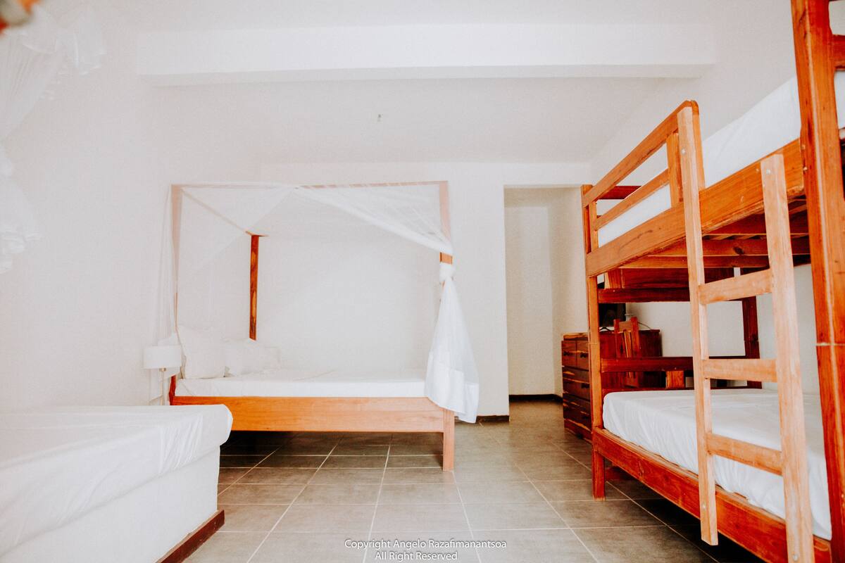 Een kamer met een enkel bed, een houten stapelbed en een kleine tafel.
