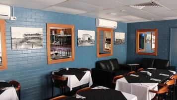 Een restaurant met blauwe bakstenen muren, zwart-wit foto's en gedekte tafels.