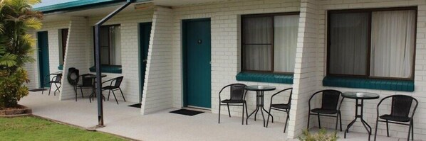 Una hilera de habitaciones de motel, cada una con zona de estar, puerta y ventana.