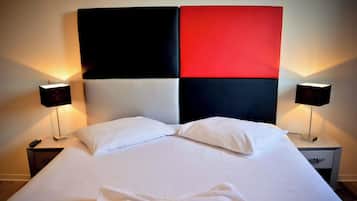 Quarto de hotel com uma cama grande, duas mesas de cabeceira e duas luminárias de parede.