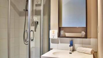 Un baño moderno con ducha envuelta en vidrio, tocador con espejo y lavabo.