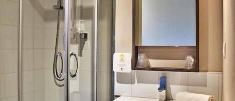 A modern bathroom with a glass-enclosed shower, a vanity with a mirror, and a sink.