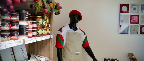 A mannequin dressed in a red and green outfit, standing in a store with shelves of jars and boxes.
