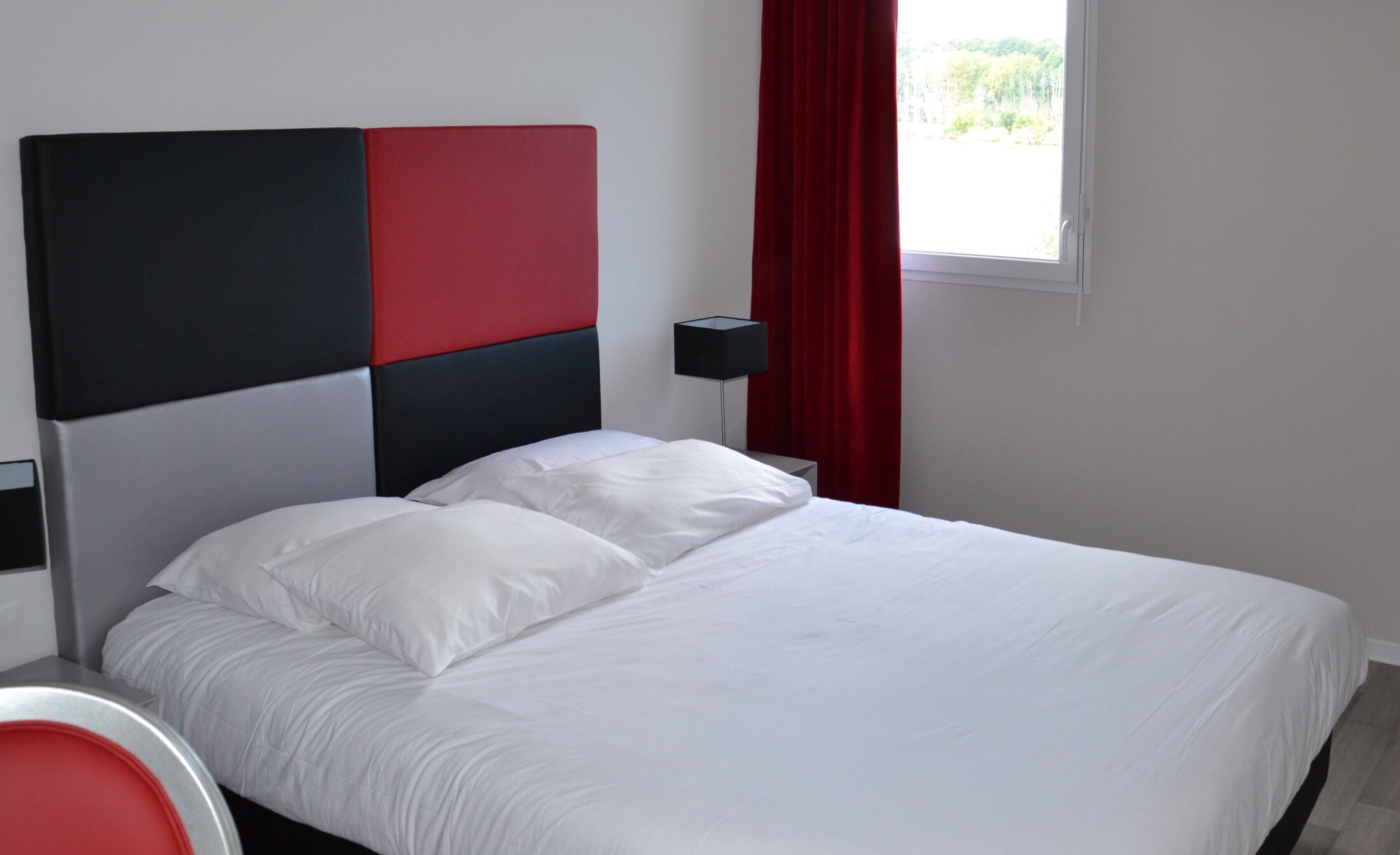 Un dormitorio moderno con una cama, una mesita de noche y una cortina roja.