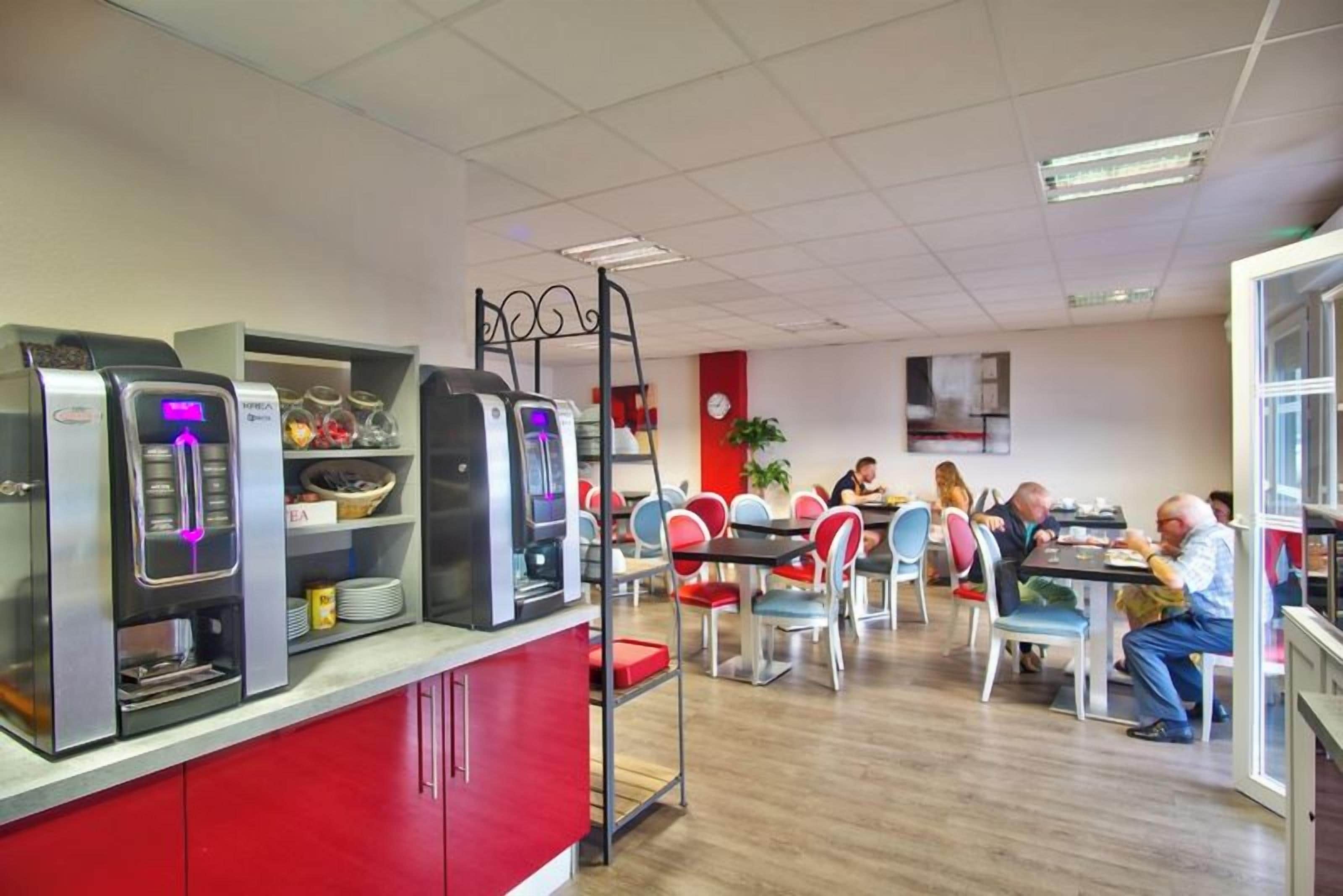 Una cafetería con varias mesas y sillas, una máquina de café y estantes con productos alimenticios.