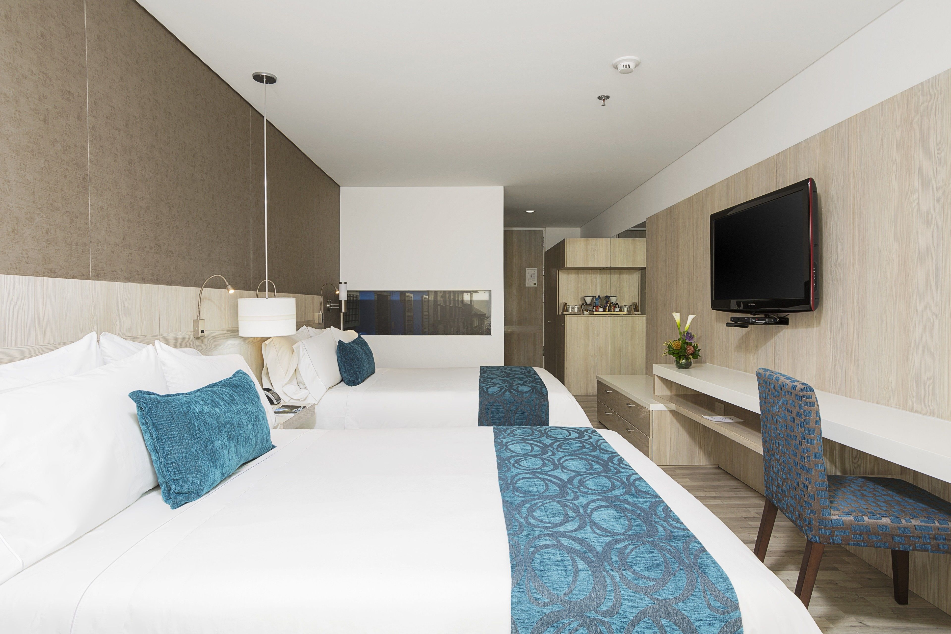 A modern hotel room with a large bed, a desk, and a TV.