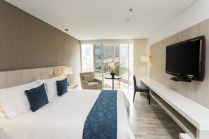 Relax in a spacious room with a large bed, flat-screen TV, and seating area, plus a balcony offering a city view.