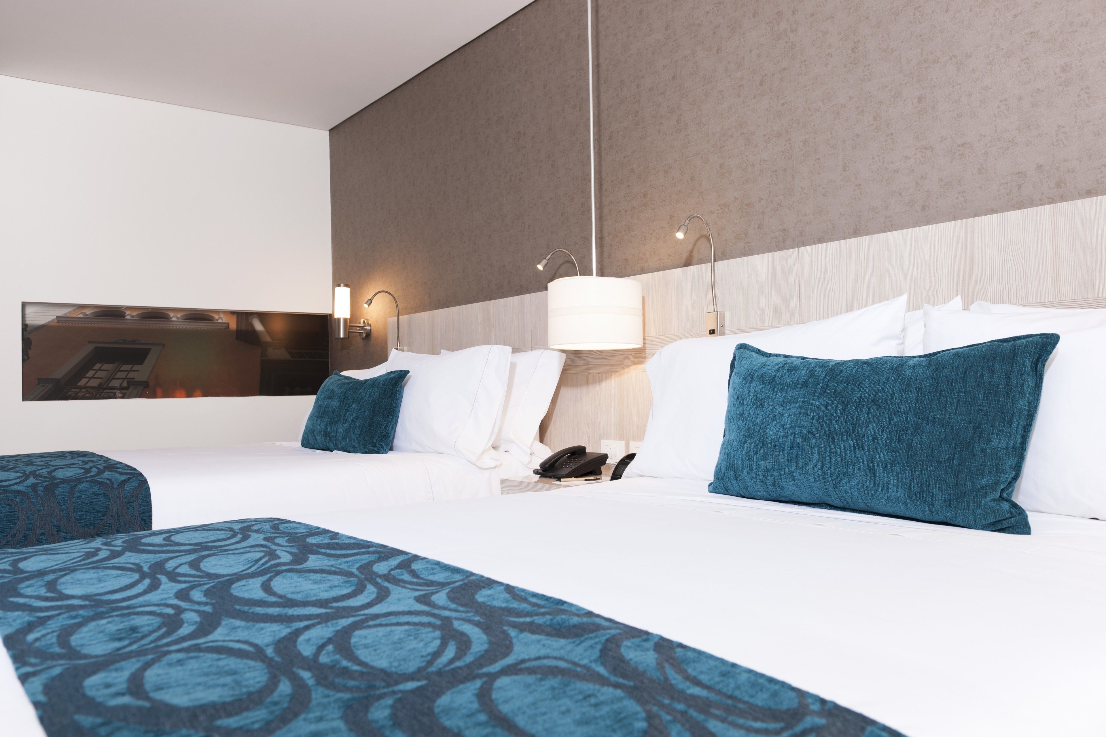 A hotel room with a large bed, two bedside tables, a wall-mounted TV, and a modern lamp.