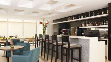 A modern bar area with a counter, bar stools, and a variety of liquor bottles.