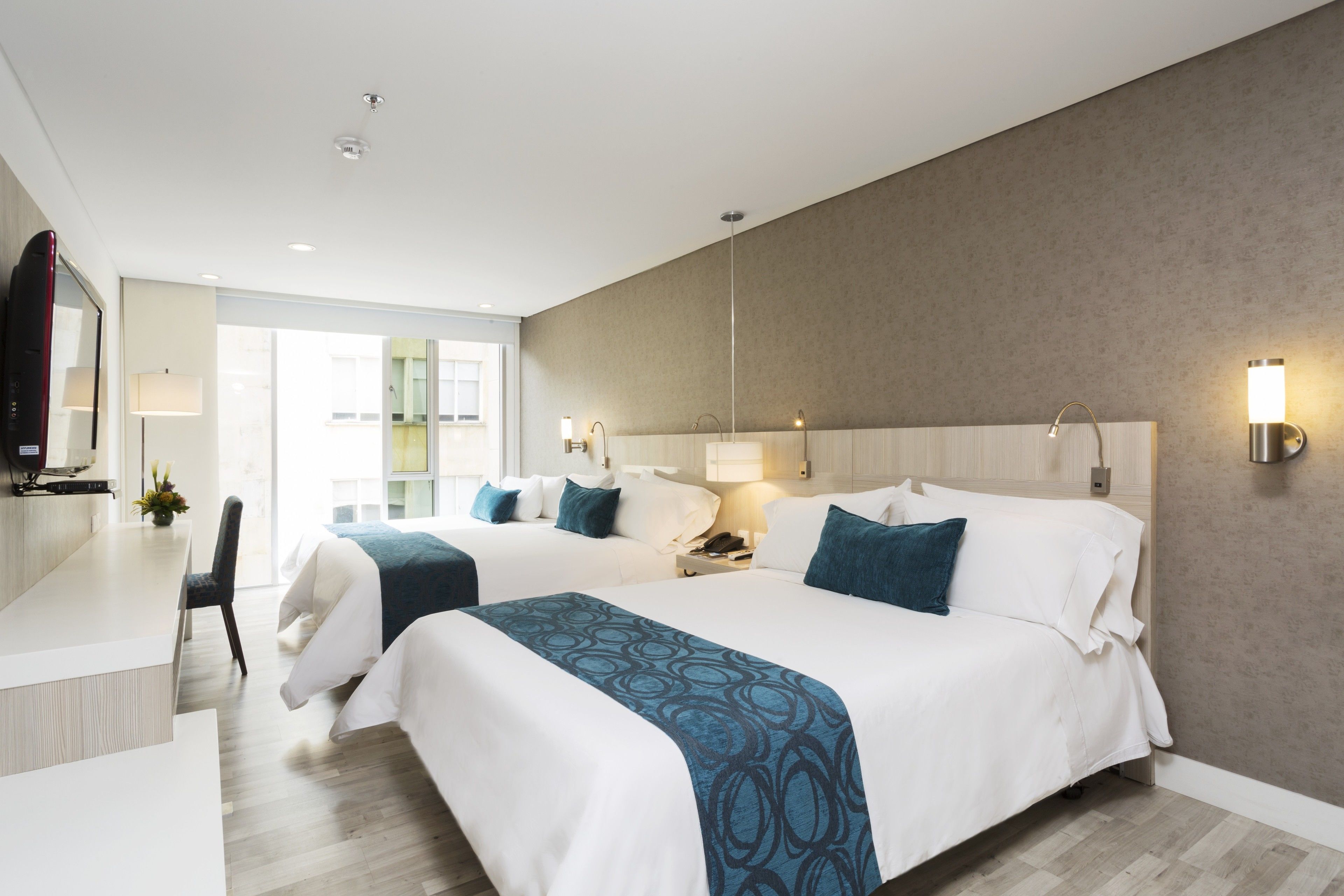 Habitación de hotel con dos camas, un escritorio y una zona de estar.